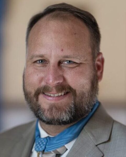 Smiling bearded man in suit wearing medal